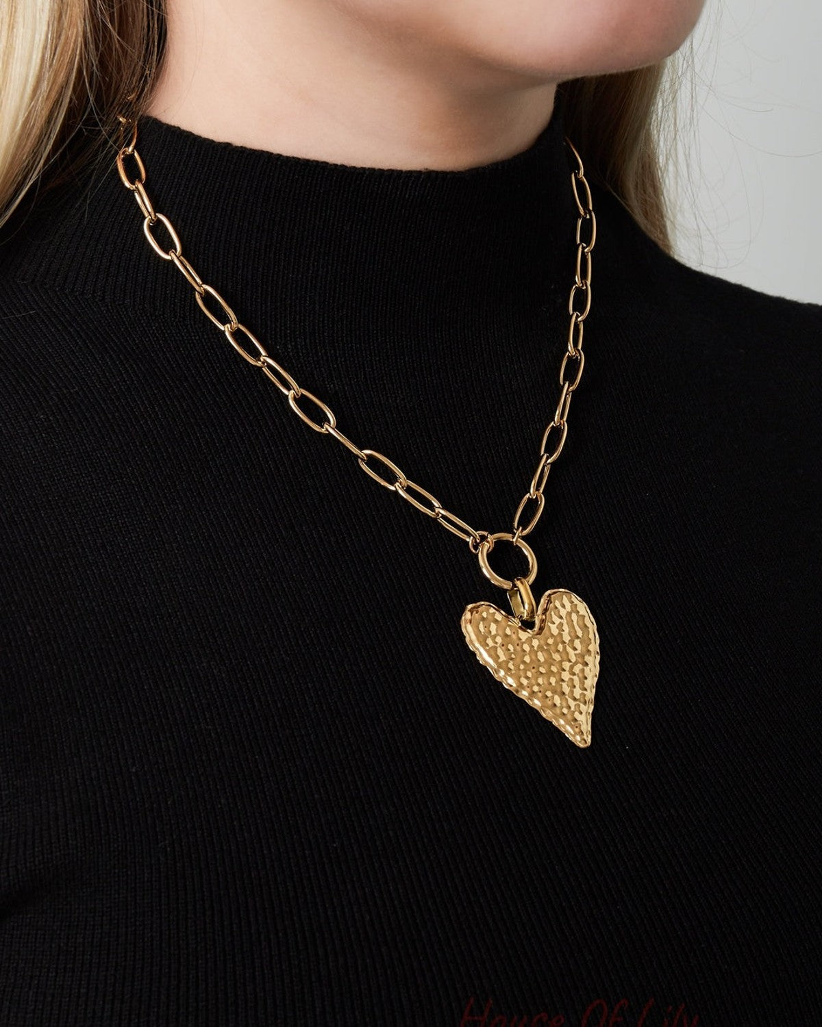 Woman wearing a gold-plated hammered heart pendant necklace paired with a black top