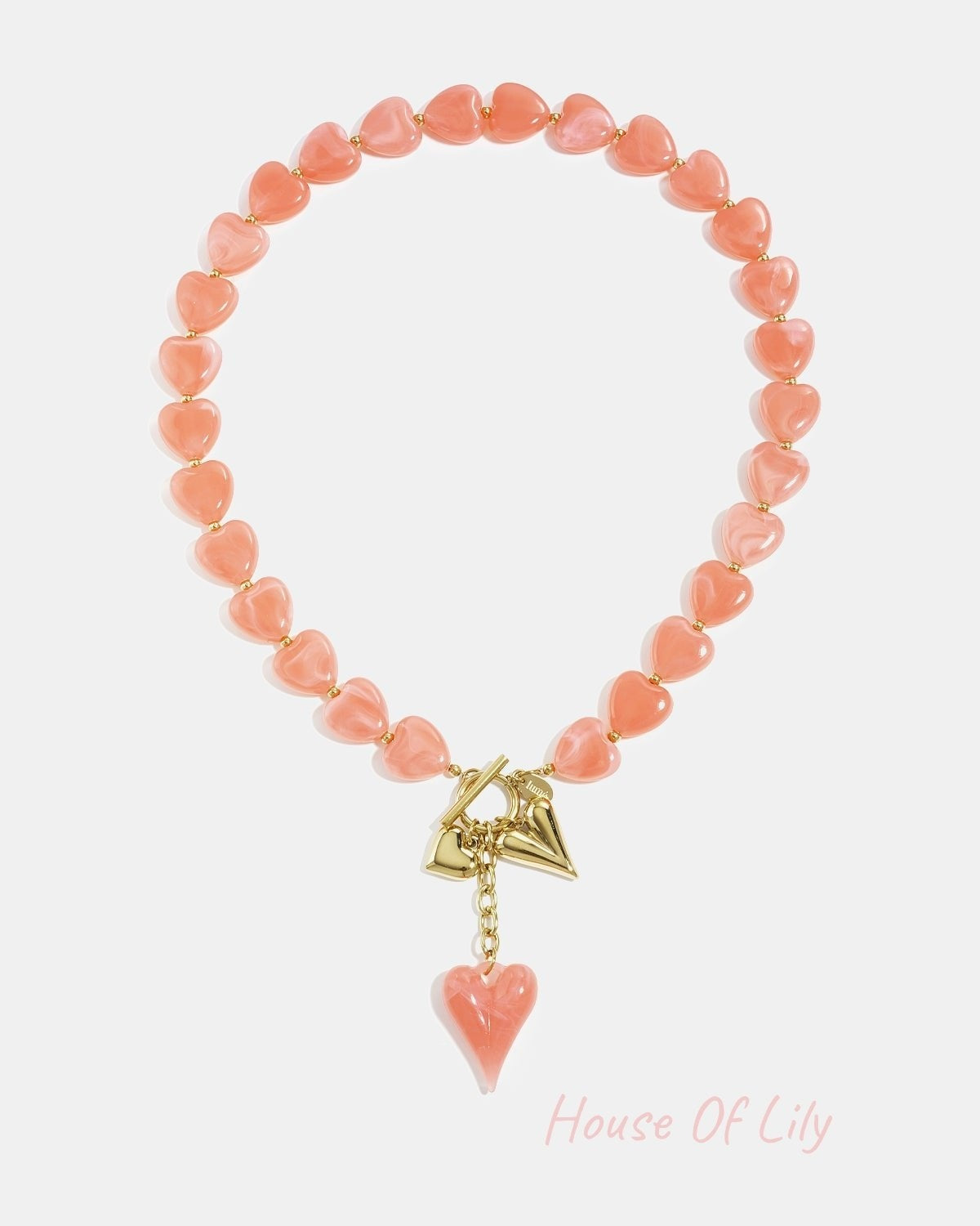 Amber brown heart bead necklace displayed on white background with gold charms and toggle clasp