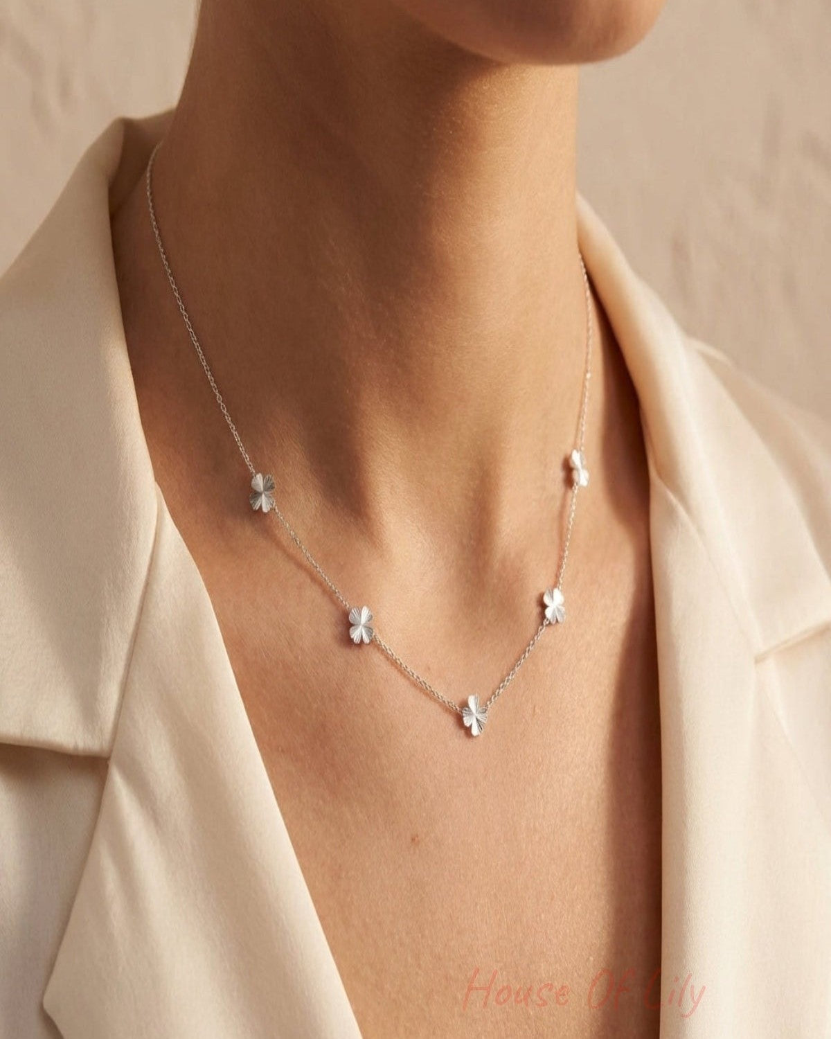 Elegant four-leaf clover necklace with fine craftsmanship on a soft neutral background, showcasing stainless steel charms and adjustable chain for women.