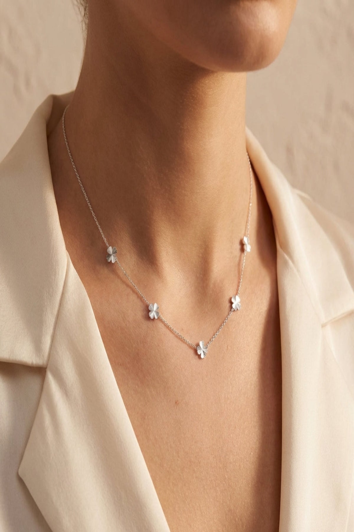 Elegant four-leaf clover necklace with fine craftsmanship on a soft neutral background, showcasing stainless steel charms and adjustable chain for women.