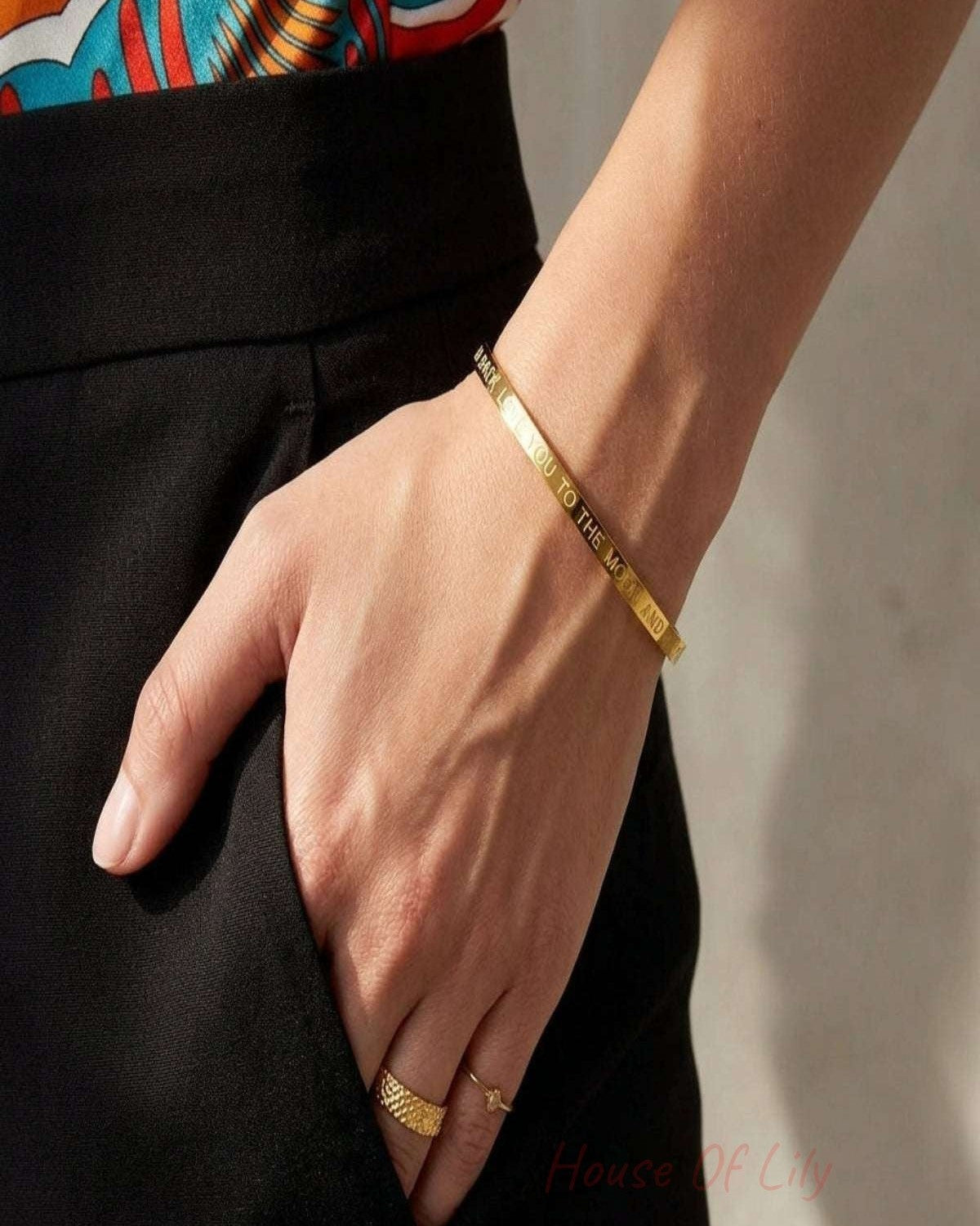 Small slave bracelet with 'love you to the moon and back' inscription, showcasing micro-texture on neutral fabric.