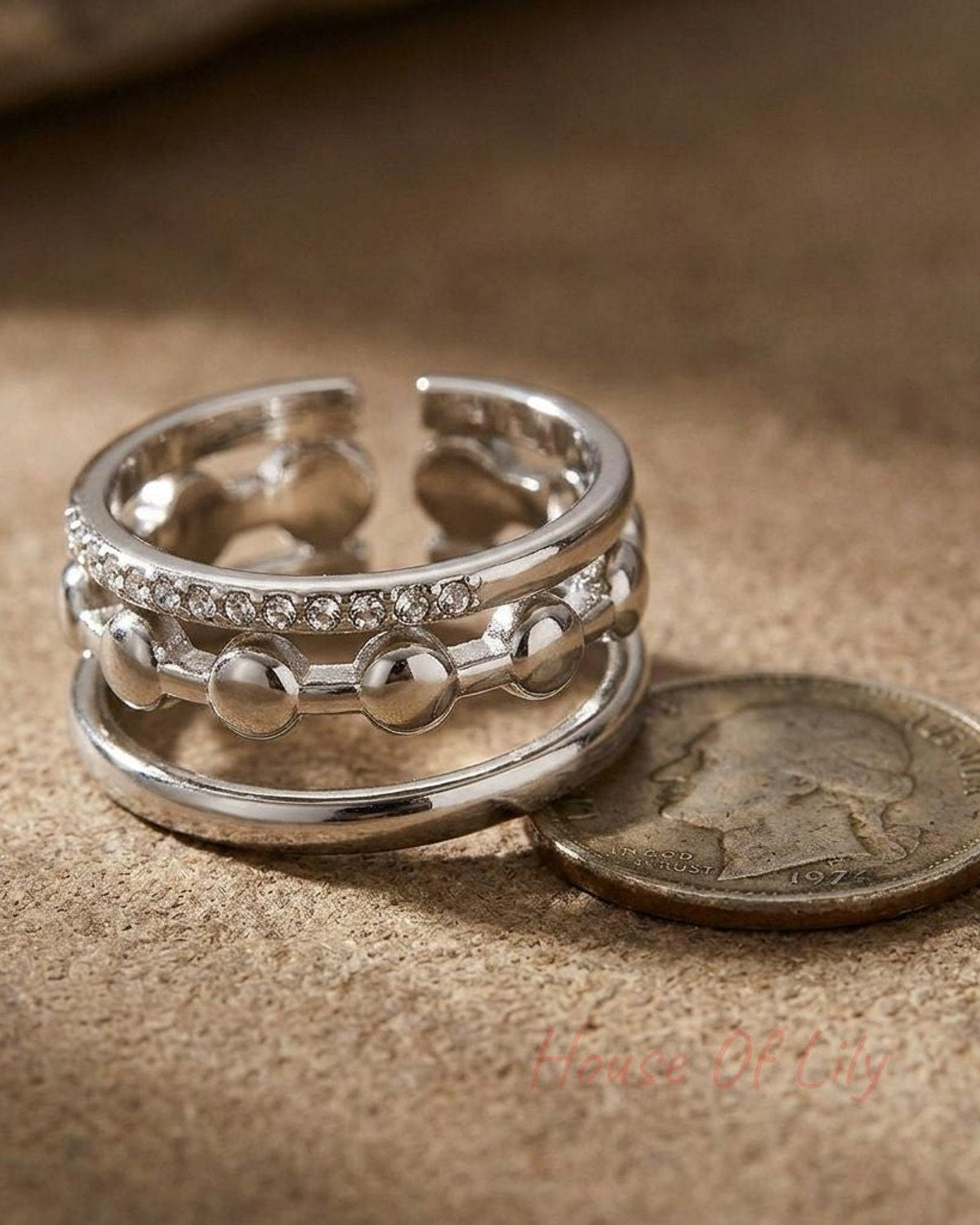 Close-up of layered Triple Tier Sparkle Ring with rhinestones on textured surface, highlighting its elegance and irregular shape.