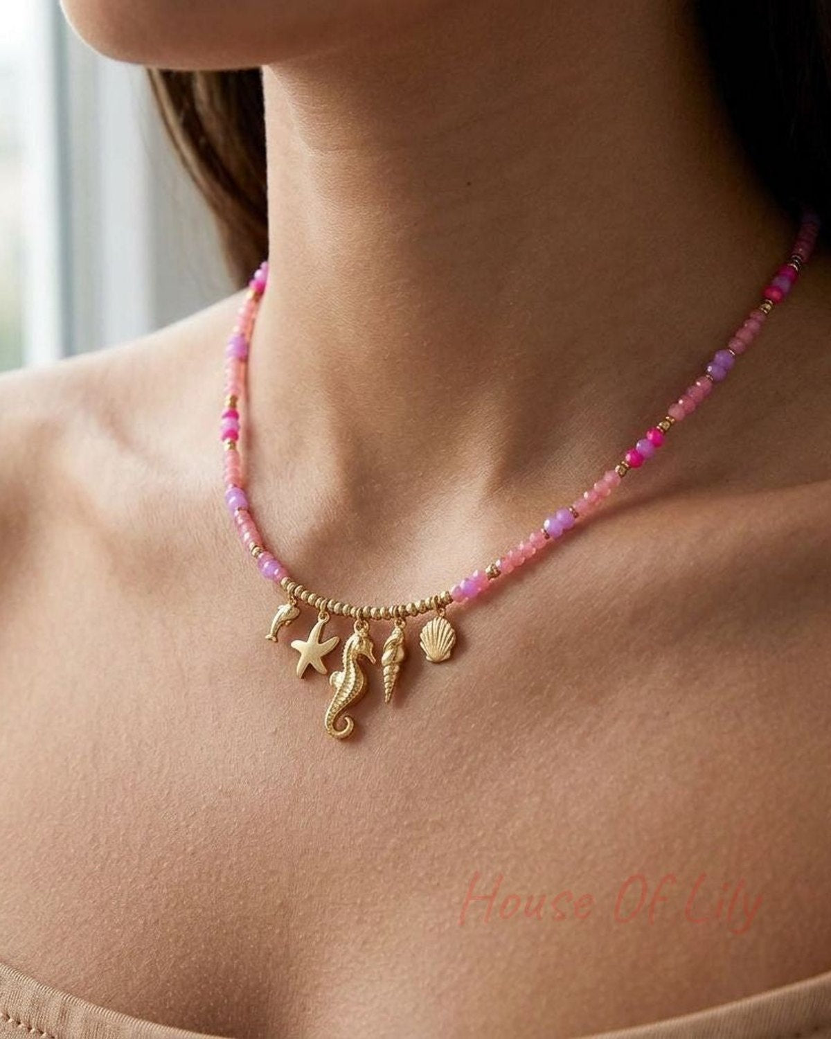 Close-up of Dolphin Core Charm necklace with starfish and glass beads on model's collarbone in soft daylight, highlighting oceanic casual style and delicate textures.