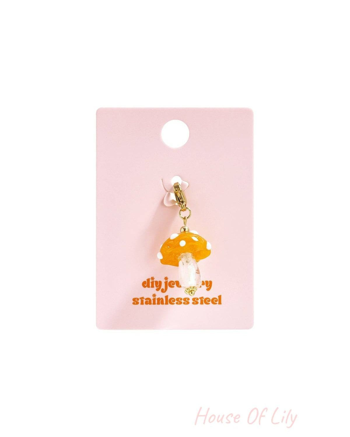Orange mushroom charm with a translucent orange cap, white dots, and clear stem, attached to a gold lobster clasp.