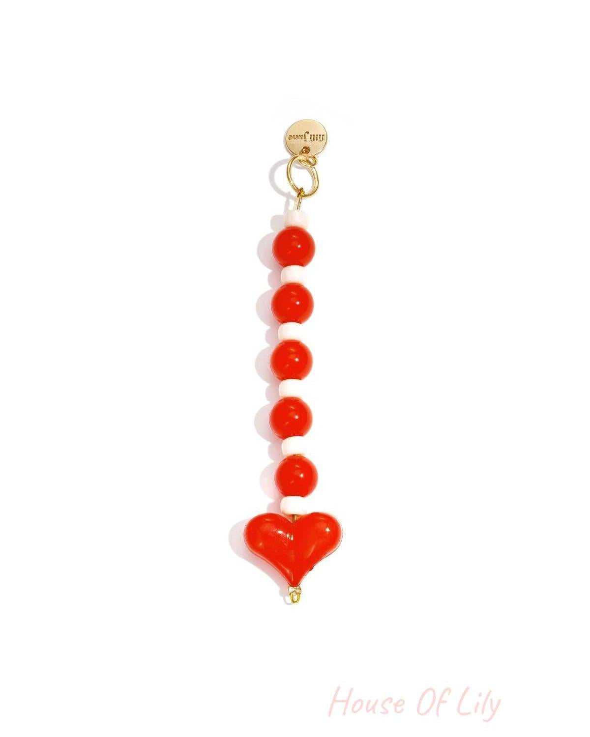 Red and white heart bead bag charm with gold clasp on white background