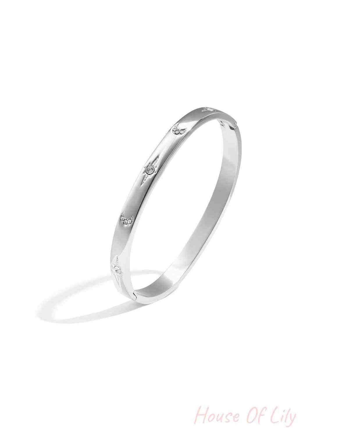 Silver-tone slim metal bangle bracelet with crystal star and crescent accents on white background