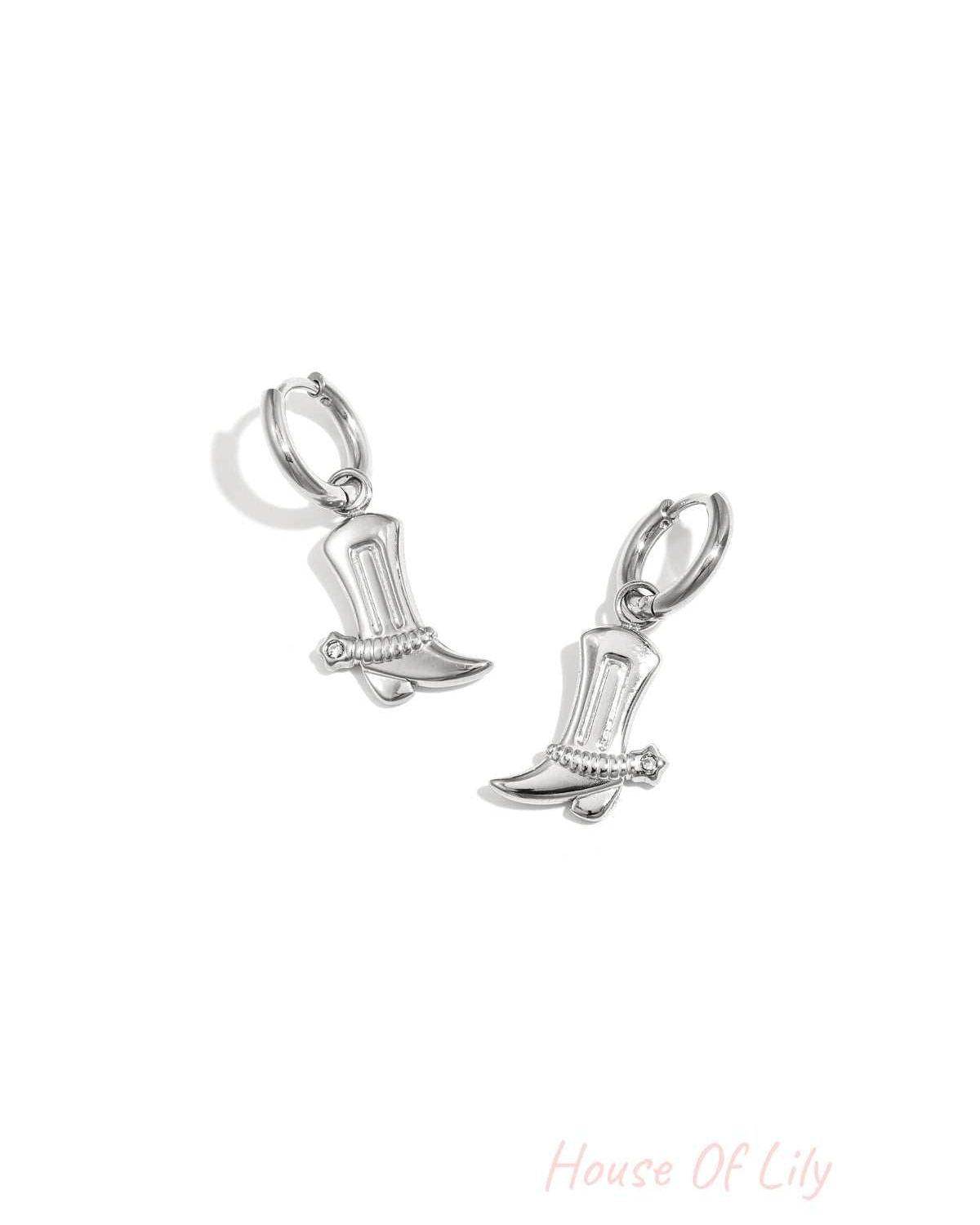 Pair of silver cowboy boot charm drop earrings with rhinestone detail on white background