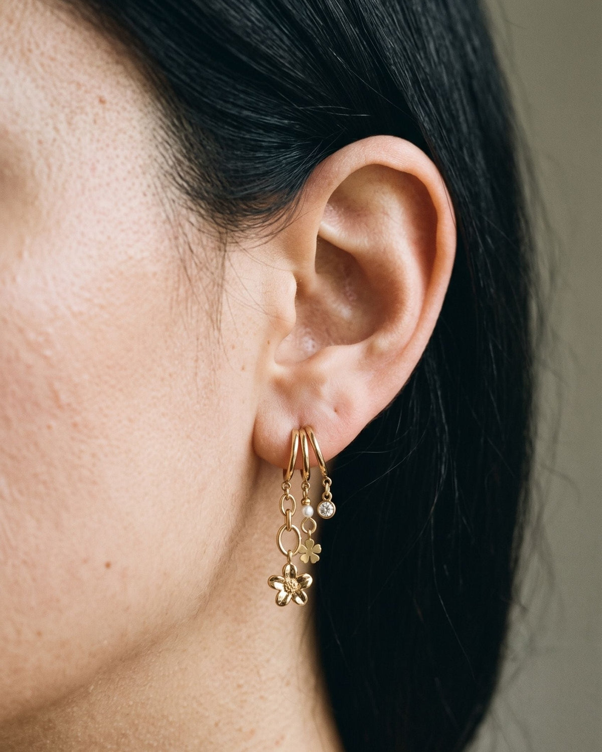 Elegant silver and gold sea shell drop earrings featuring tiny flower charms and zircon accents worn on a model ear.