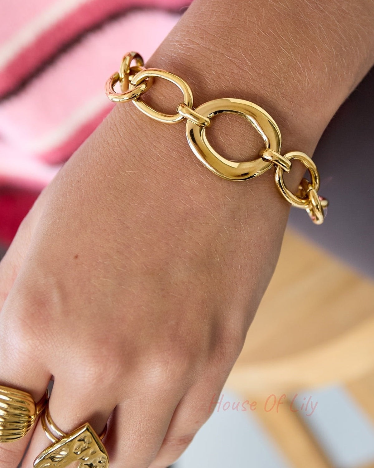 Close-up of golden chunky linked chain bracelet worn on wrist with rings