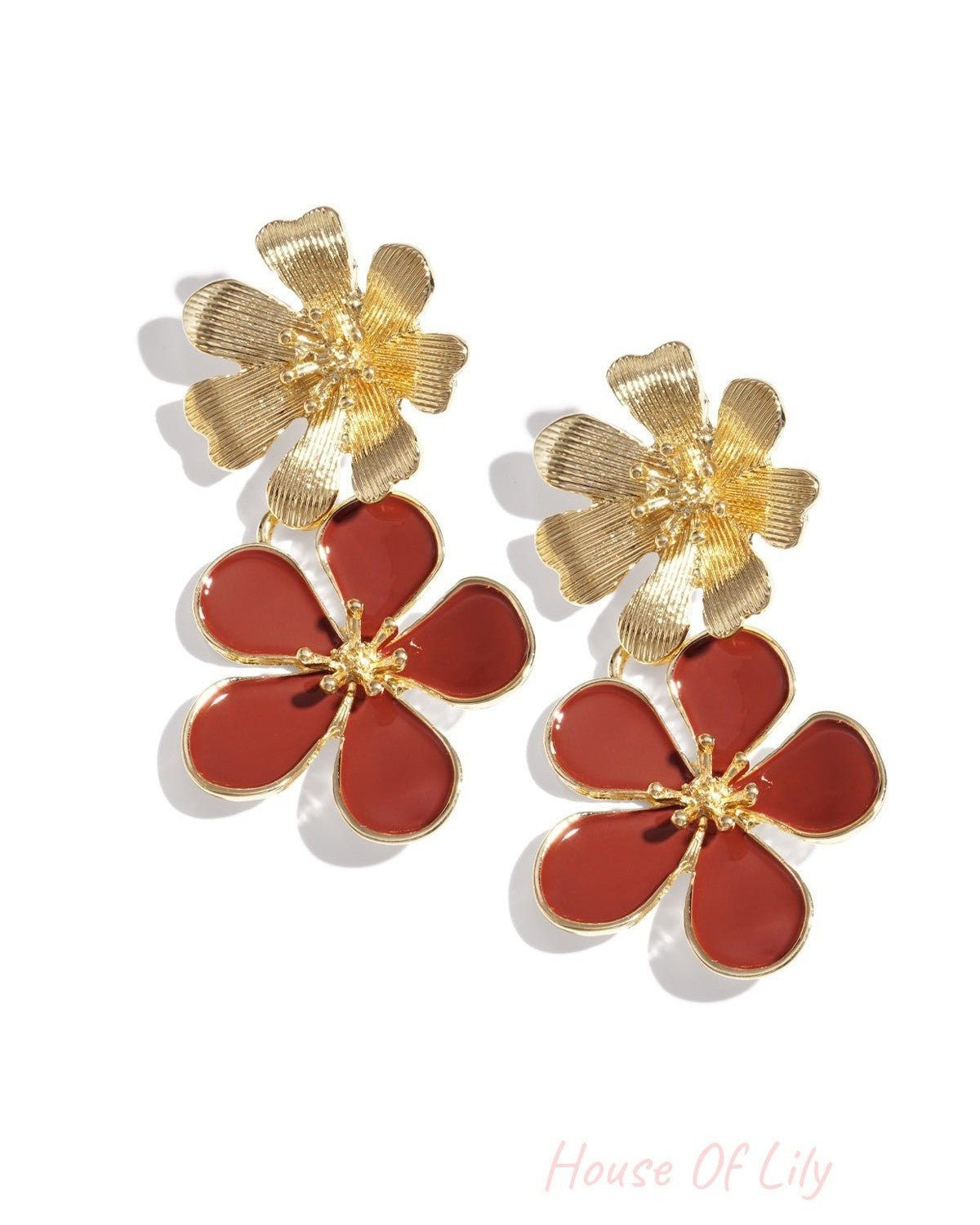 Pair of gold-tone drop earrings with textured top flower and pink enamel bottom flower on white background