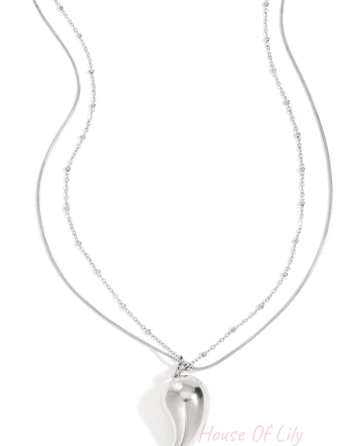 Silver layered necklace with a curved droplet pendant on a white background featuring delicate mixed chains