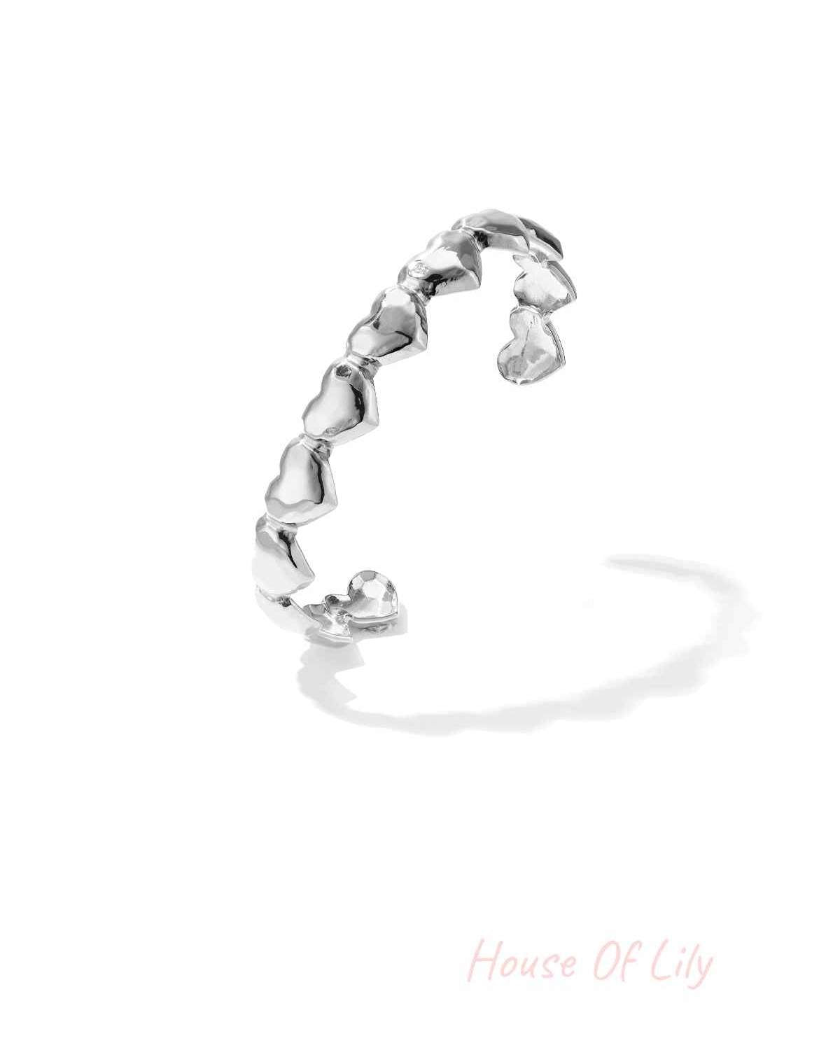 Silver dented heart cuff bracelet with open design on white background