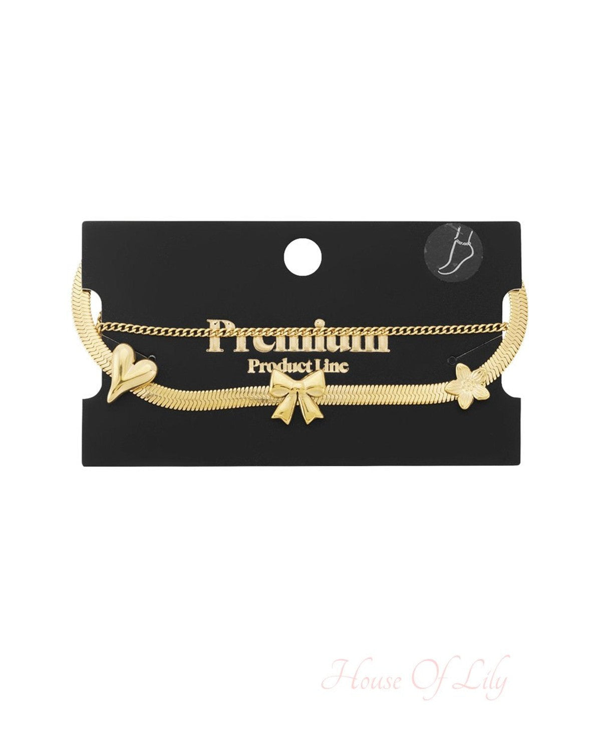 Dainty gold double-chain anklet featuring a flat snake chain with heart, bow, and flower charms on a display card.