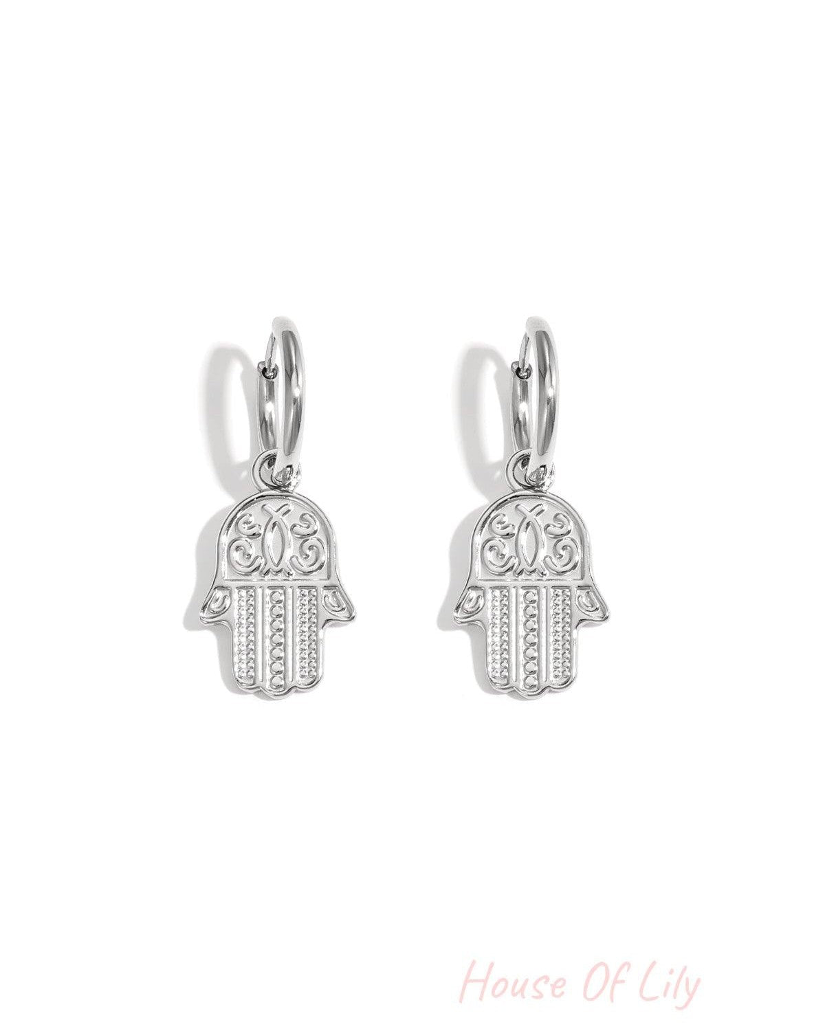 Pair of silver tone Hamsa charm drop earrings on white background
