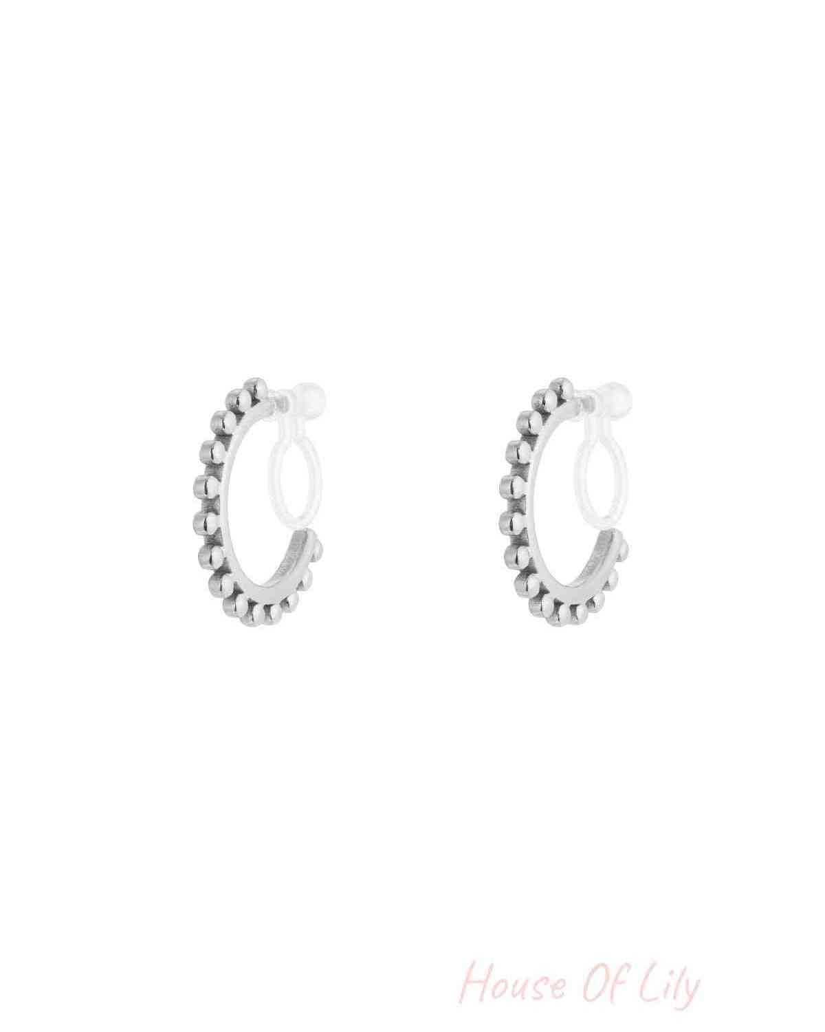 Pair of silver-tone beaded hoop clip-on earrings with clear silicone backings isolated on white background