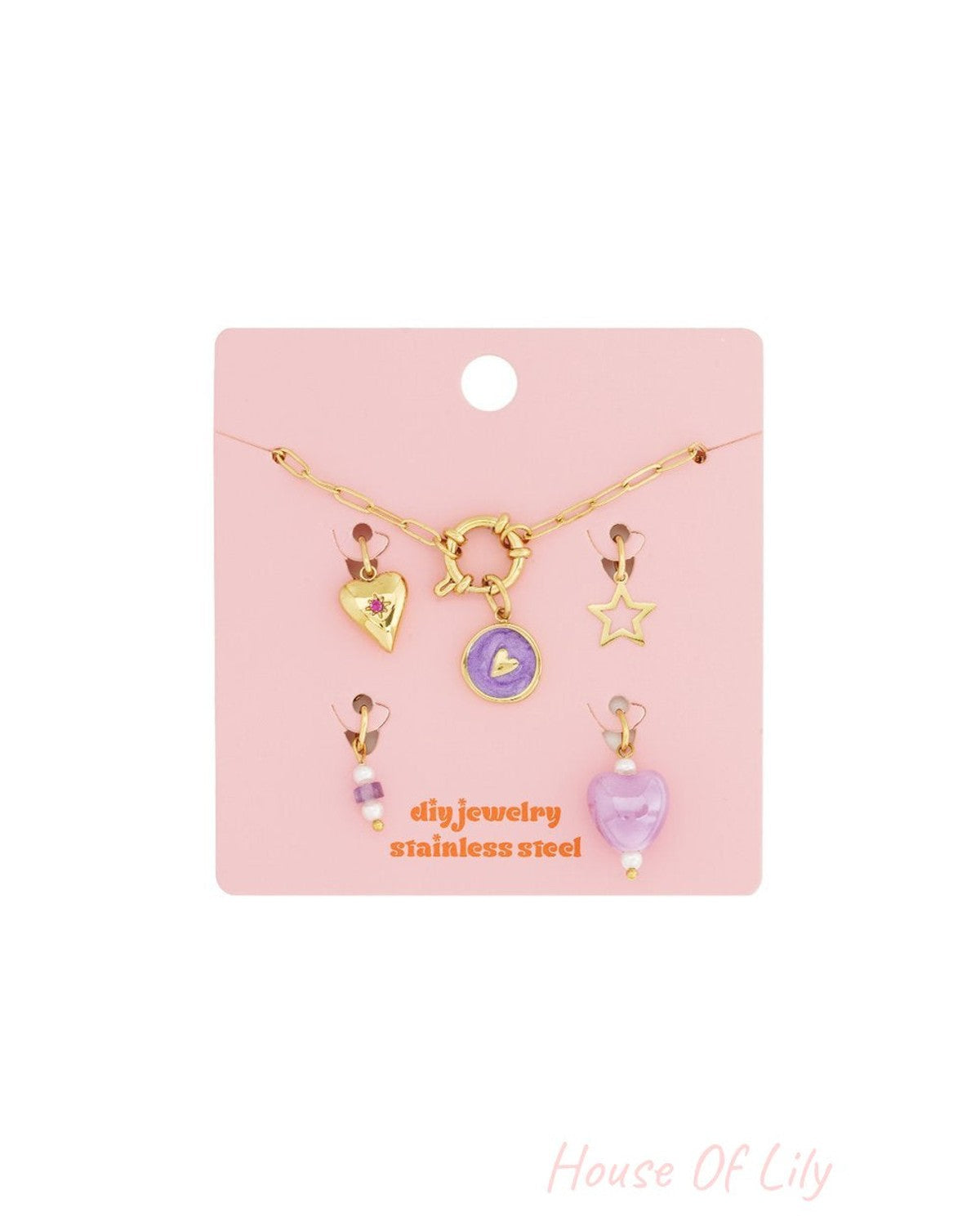 Gold-tone stainless steel modular charm bracelet kit with heart, star, and purple enamel charms on a pink display card.