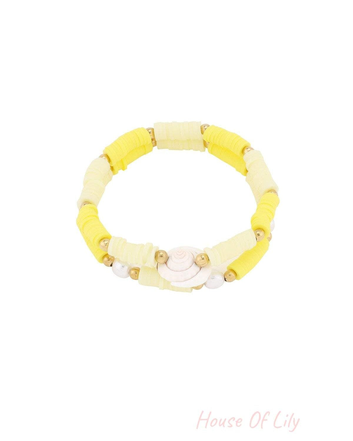 Yellow shell charm beaded bracelet with gold and polymer clay beads on white background