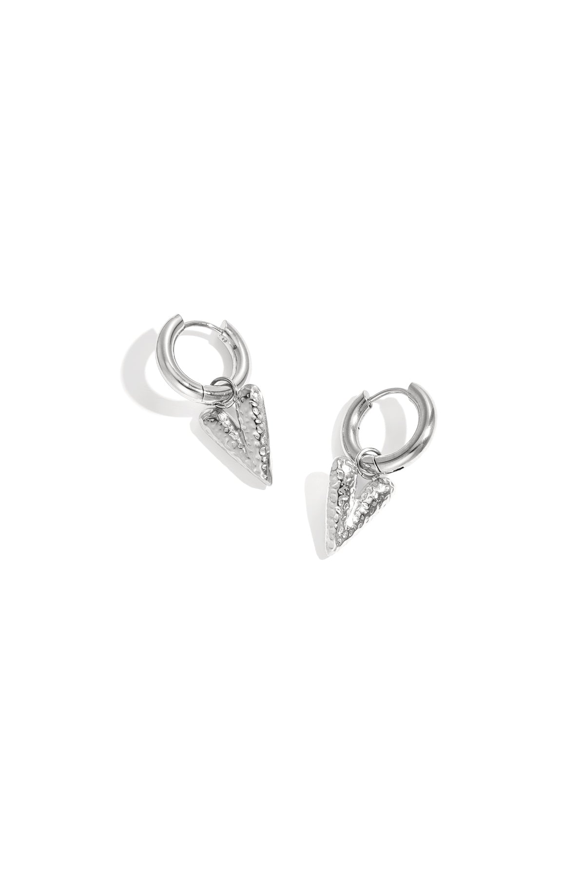 Pair of silver hoop earrings with textured heart-shaped pendants displayed on white background