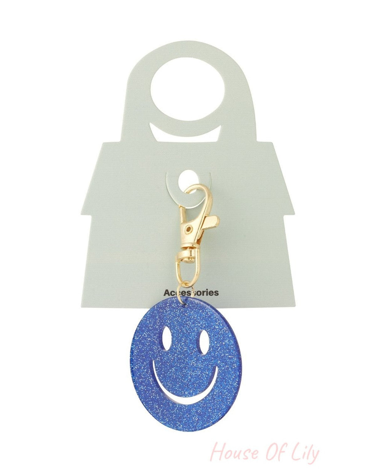 Blue glitter smiley face keychain with gold-tone lobster clasp on a branded light green display card.