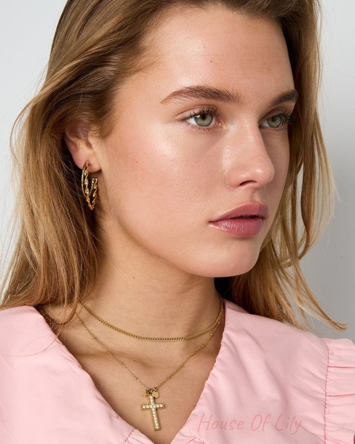 Model wears gold Iconic Y2K Cross necklace with rhinestones and matching gold twisted hoop earrings.