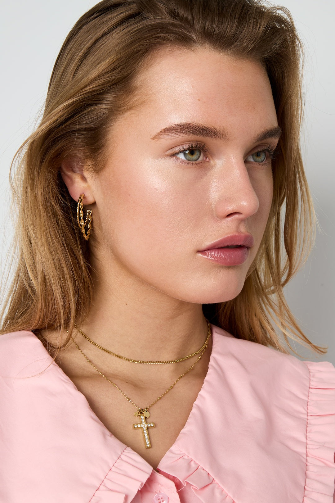 Model wears gold Iconic Y2K Cross necklace with rhinestones and matching gold twisted hoop earrings.