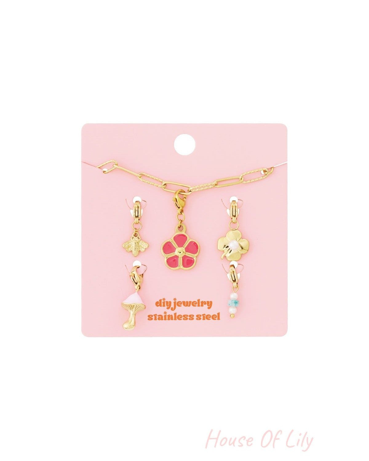Gold link charm bracelet kit on pink card with bee, pink flower, clover, mushroom, and beaded charms.