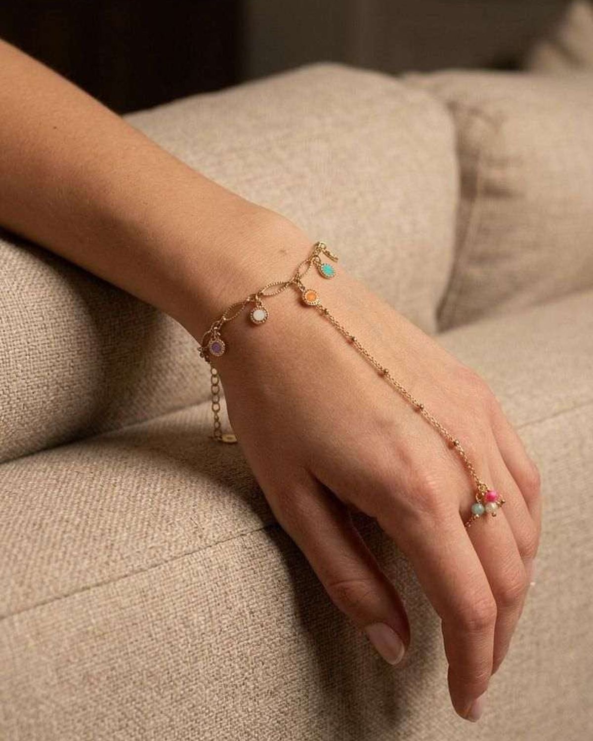 Woman's wrist wearing the 'Cool Vibe Chain' bracelet, relaxed on a beige sofa, highlighting its lightweight, adjustable chain and subtle elegance.