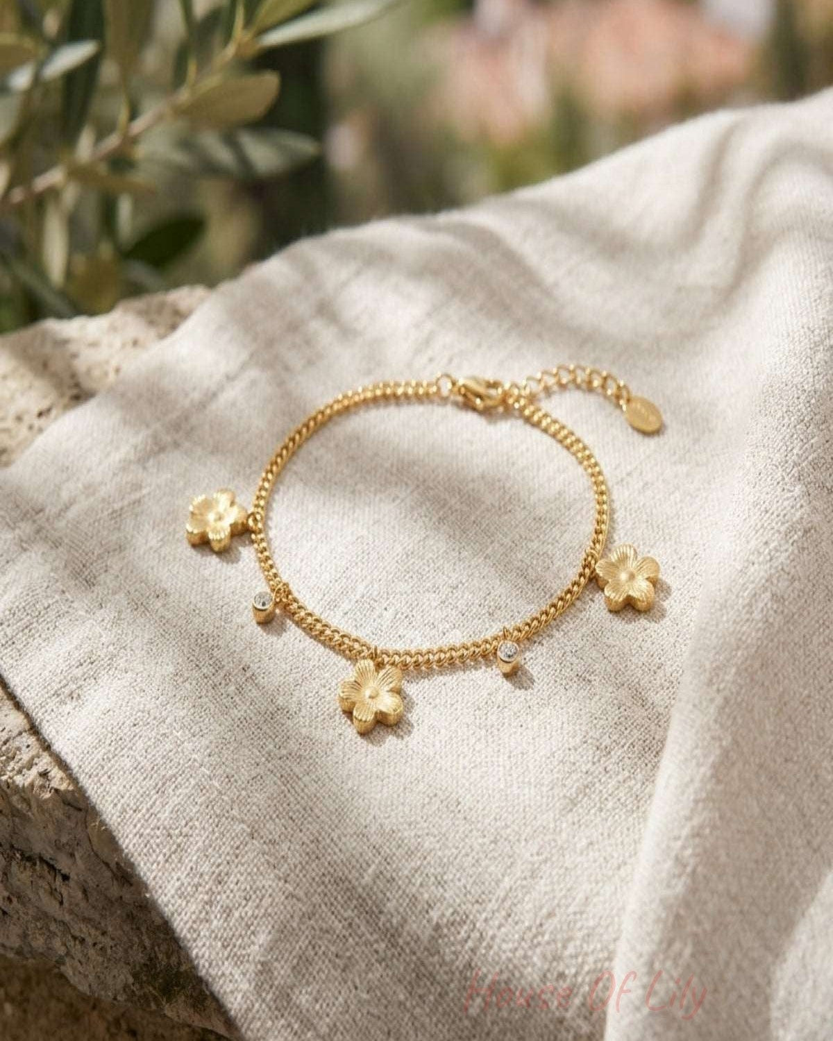 Small flower-shaped stainless steel bracelet resting on natural wood surface, showcasing its gleaming finish and delicate floral design.