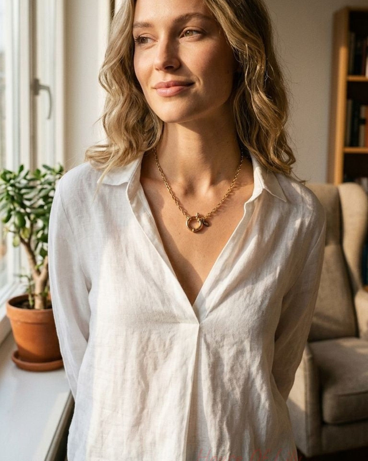 Model wearing the Golden Hour Toggle necklace styled with a light blouse in a cozy indoor setting.