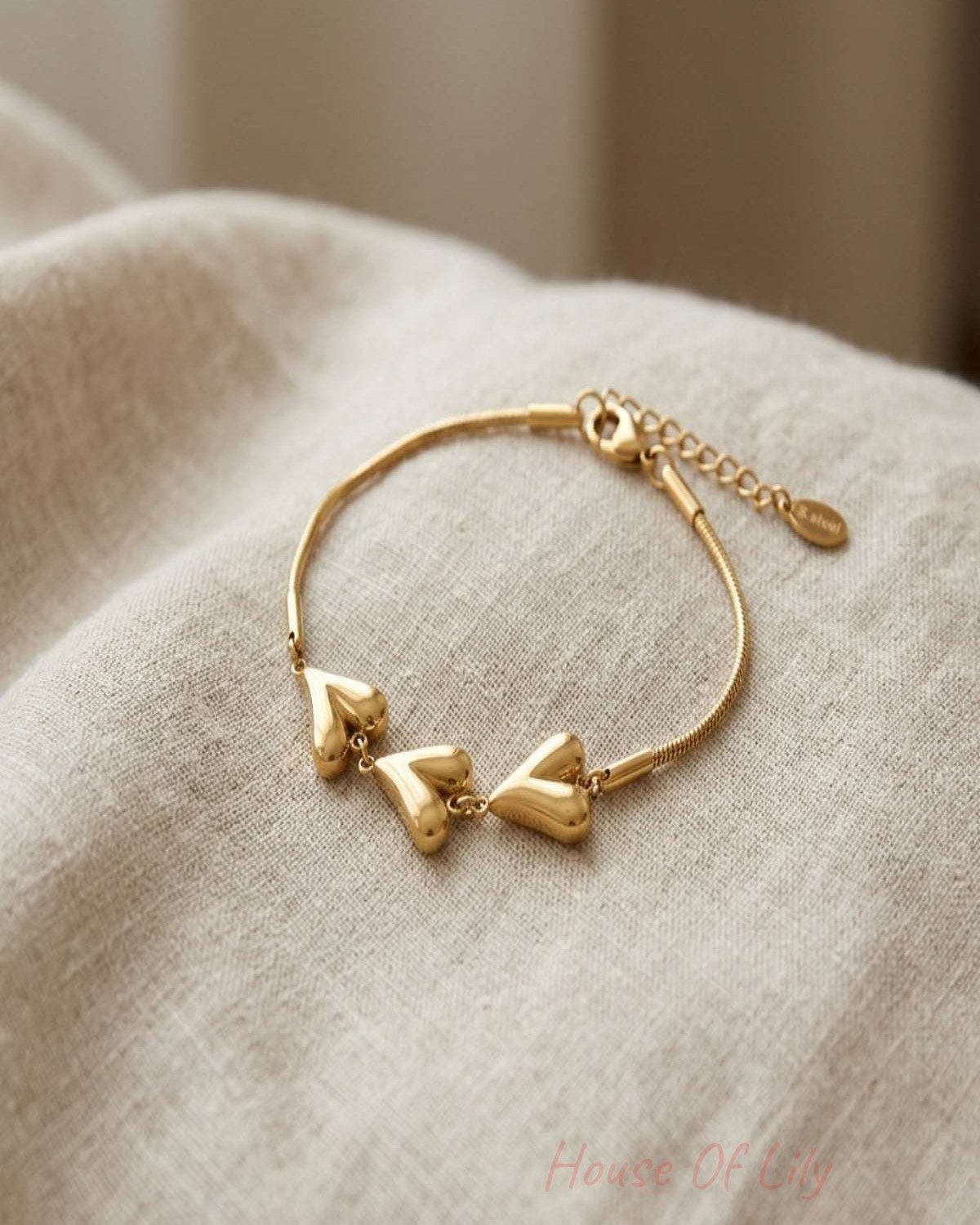 Close-up of hearts unfolded bracelet with heart-shaped links on textured surface, highlighting its stainless steel shine and delicate design.