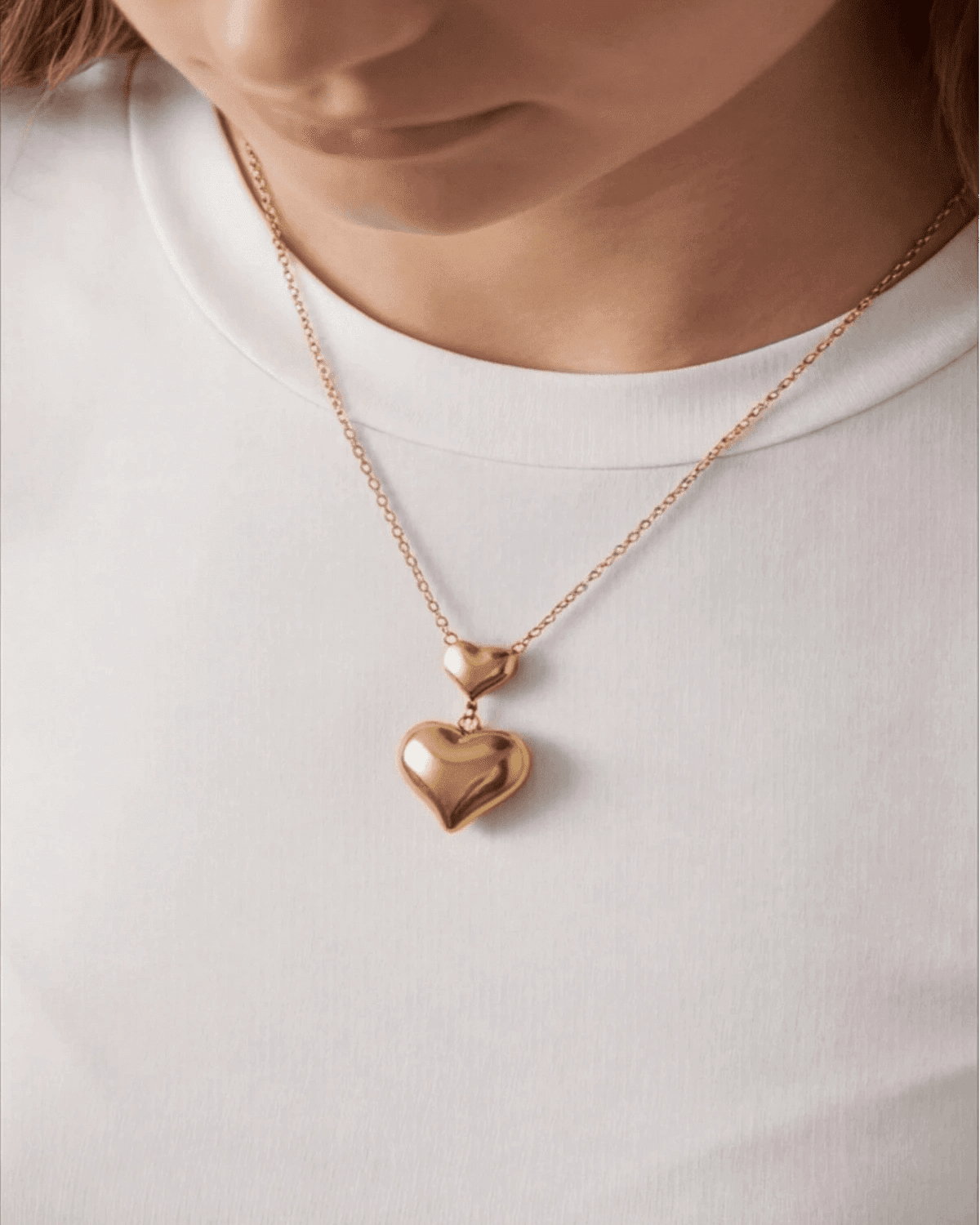 Gold heart-shaped pendant necklace on a white shirt