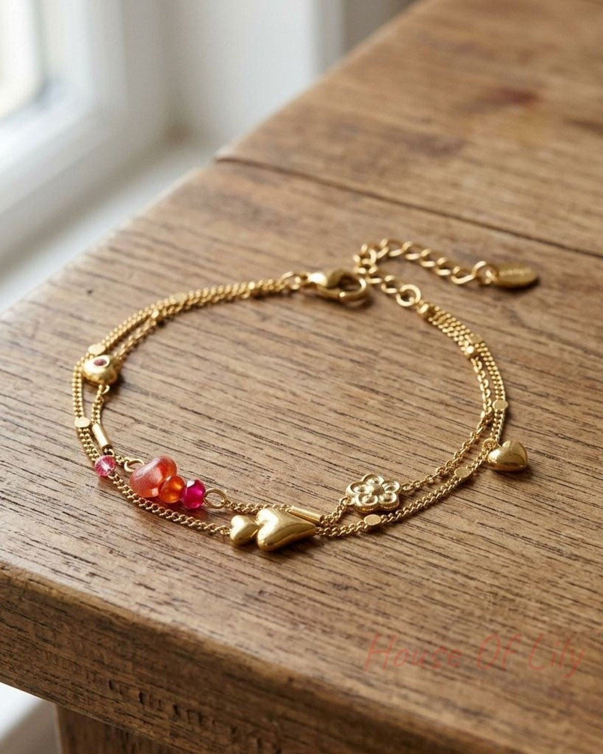 Close-up of layered heart charm bracelet with rhinestones and natural stones on wooden surface