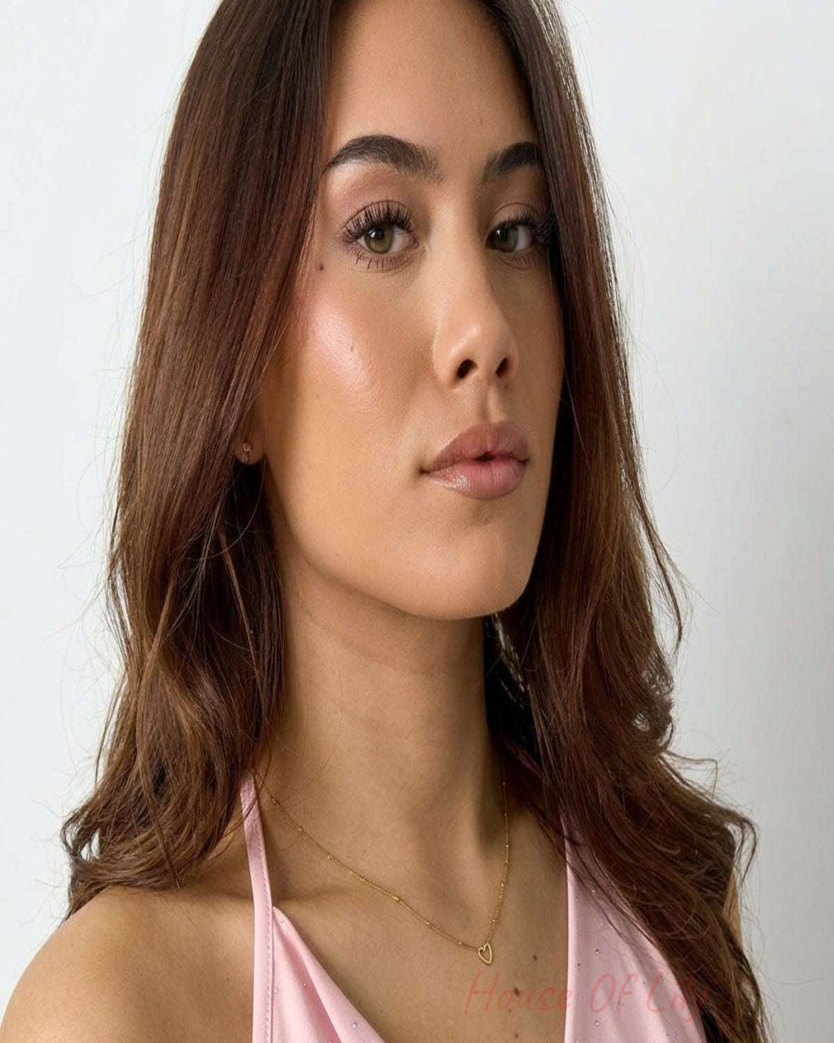 Small open heart pendant necklace in gold color worn by a woman, emphasizing its delicate and minimalist design.