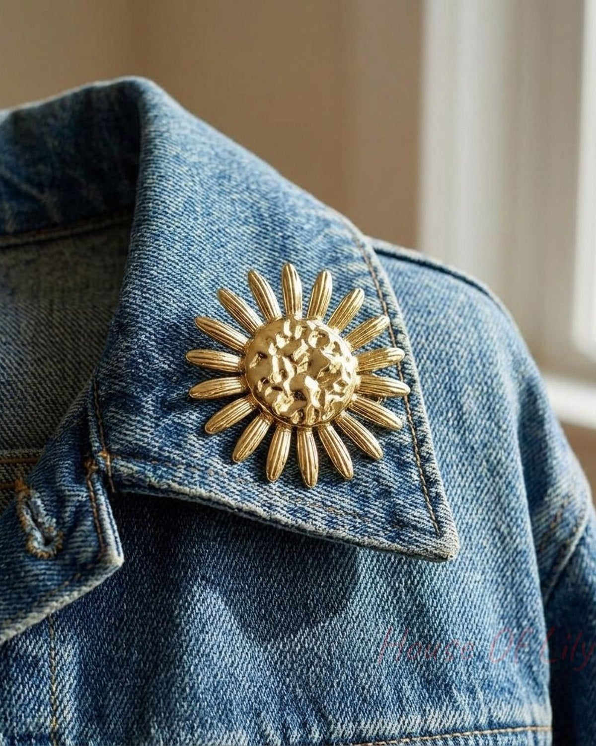 Delicate petal-shaped pin on denim jacket lapel, stainless steel finish, softly lit by natural daylight highlighting intricate details.