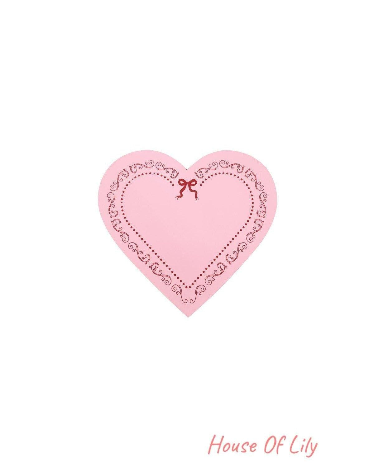 Pink heart-shaped lid featuring delicate red decorative border and bow design