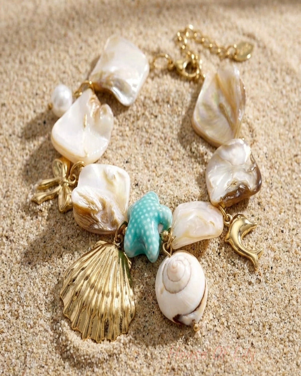 Close-up of seaside charm bracelet featuring natural shell pieces, beach charms like scallop shell, starfish, dolphin, on textured background.