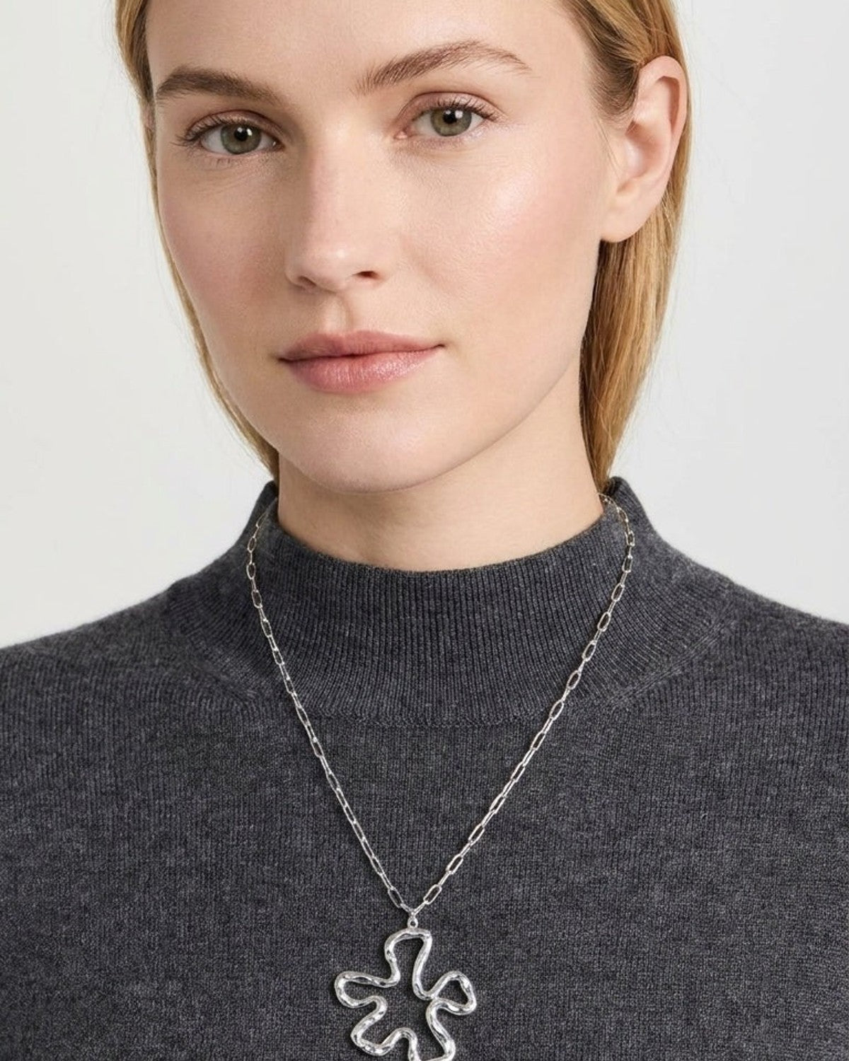 Model wearing the Iconic Lily Flower silver necklace with a hammered pendant on a chain.