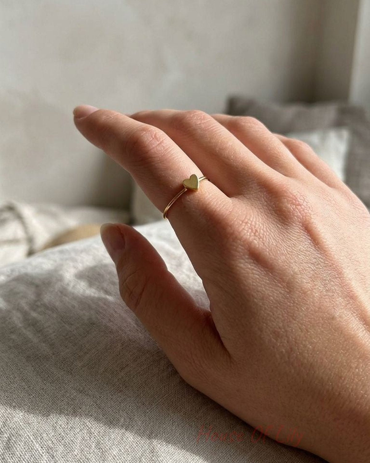 Close-up of the Little Heart Energy ring on finger, highlighting its minimalist stainless steel design and tiny heart pattern in natural daylight.