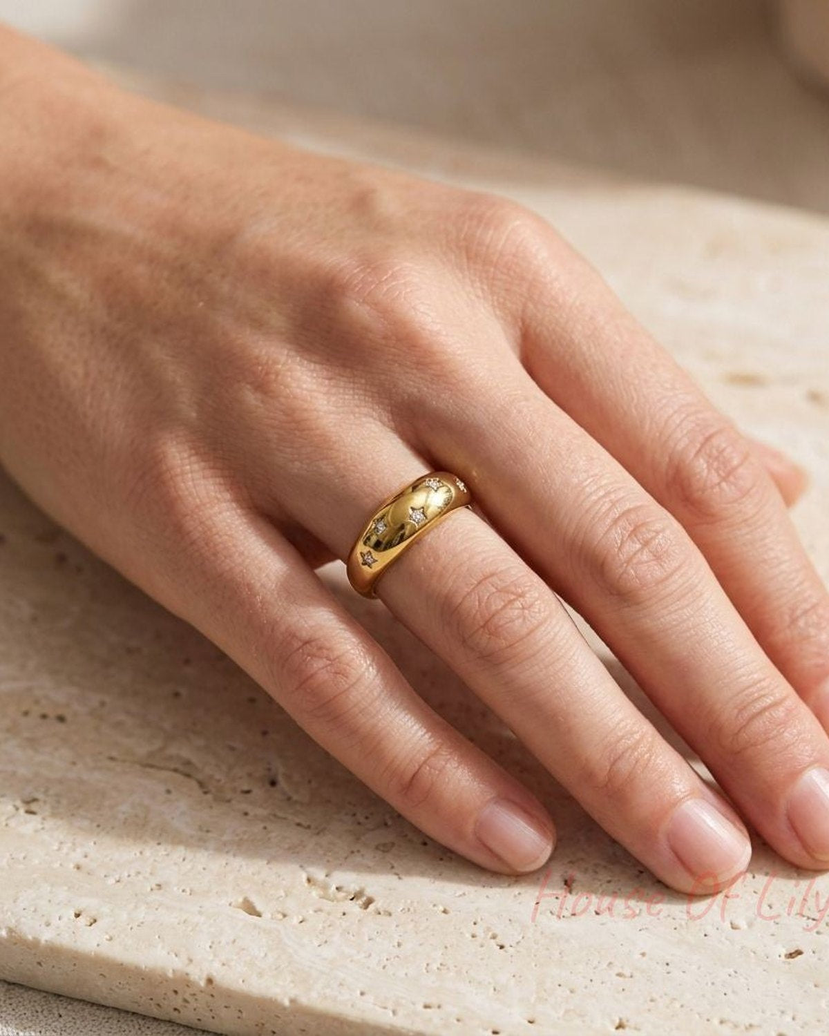 Worn on a model's ring finger, the Starry Night Band adds a subtle celestial touch to a casual chic look with soft lighting.