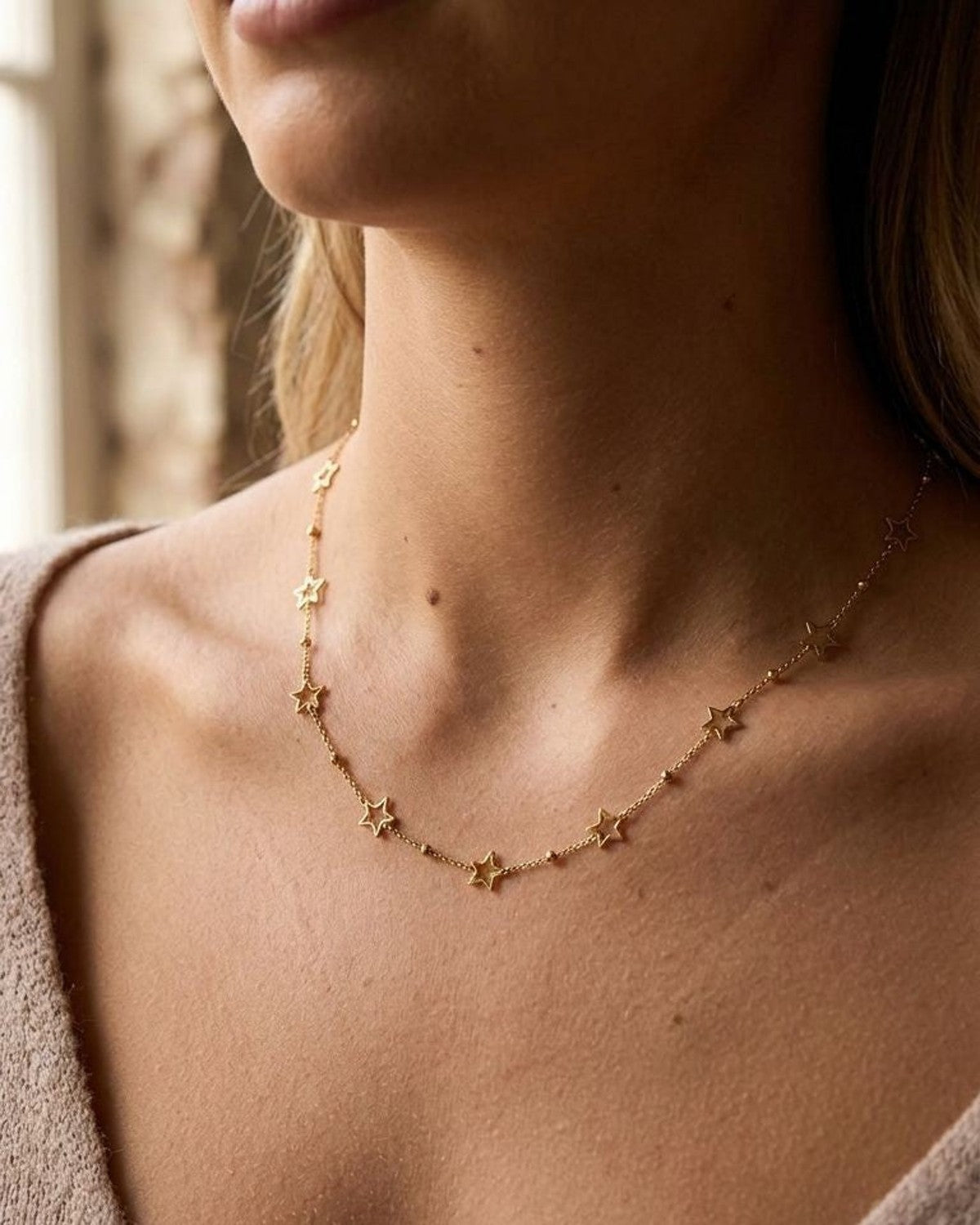 Full-body scene of woman wearing the Celestial Bestie Gold necklace in a warm, cozy indoor environment.