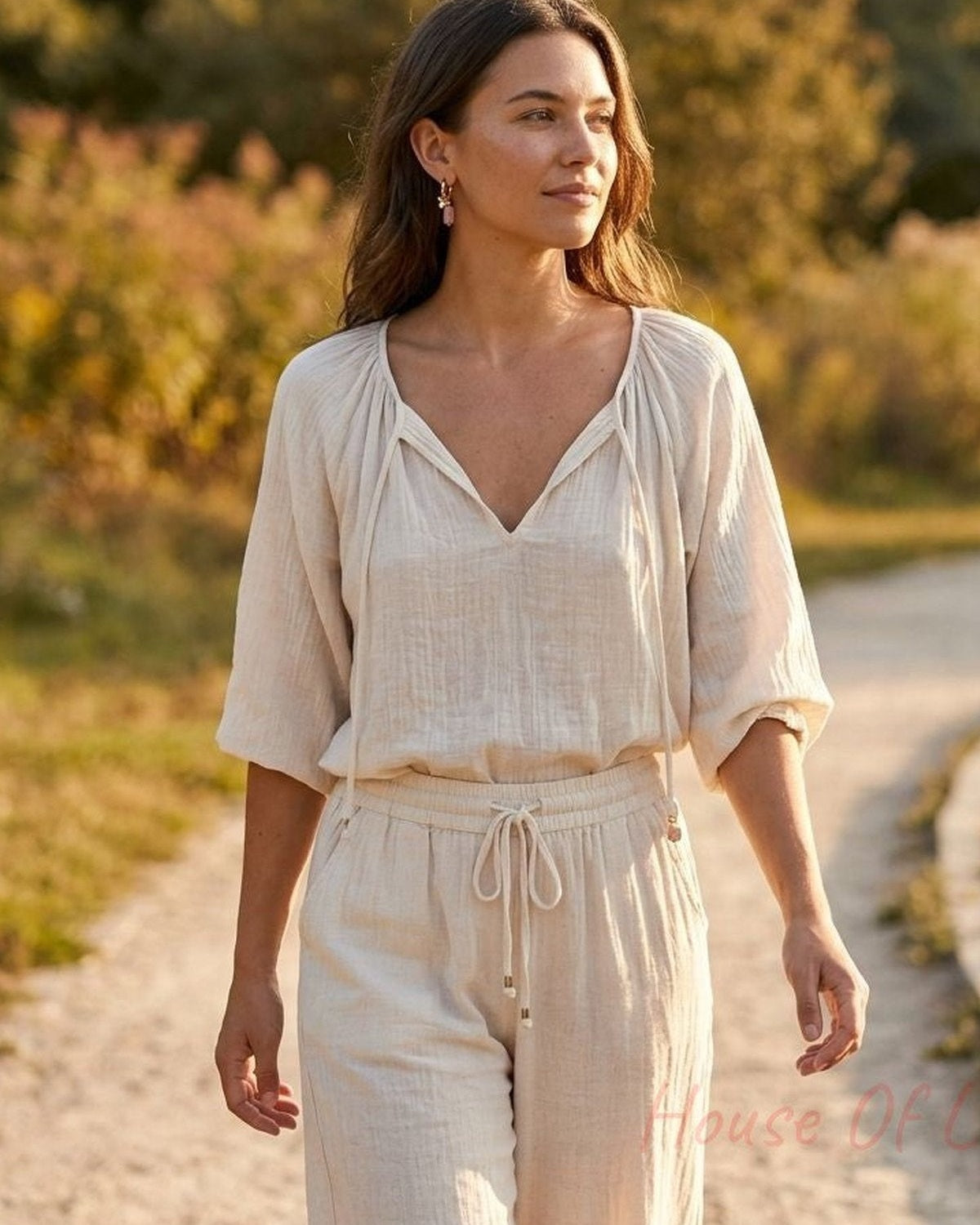 Full-body woman in a park wearing dainty charm hoops during golden hour, highlighting whimsical jewelry style.