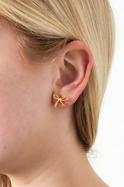 Close-up of a woman wearing one gold bow clip earring on her earlobe showcasing the delicate design