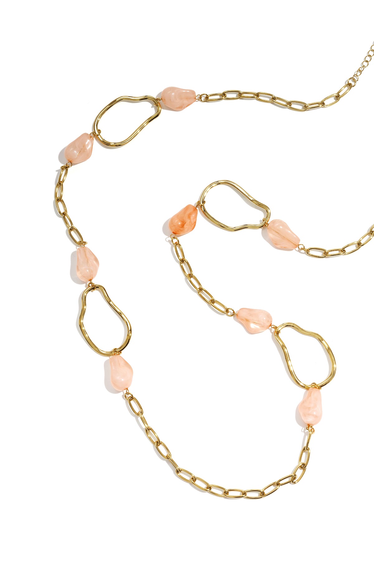 Gold chain necklace with irregular loops and soft peach-colored acrylic beads on white background