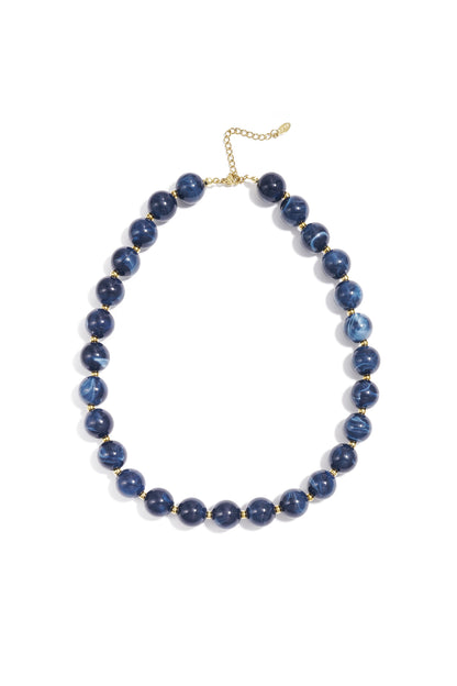 Red marbled chunky beaded necklace with gold spacer beads and adjustable gold chain on white background