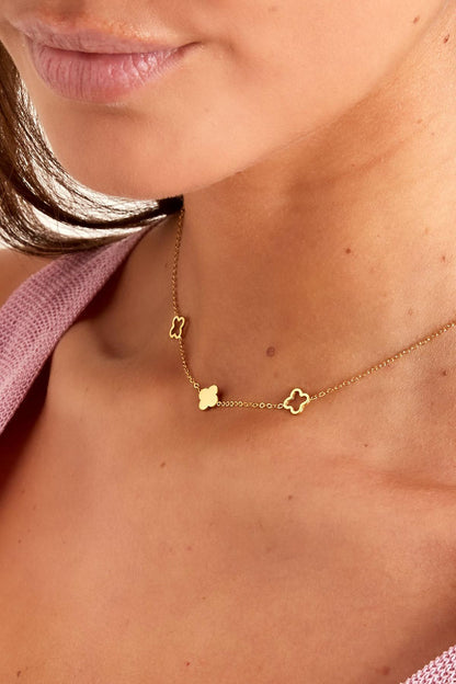 Detailed view of gold-tone clover charm necklace on model showcasing the chain and charm design