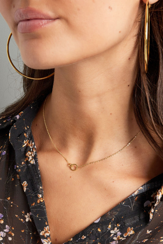 Close-up of model's neck showcasing the delicate gold linked circle necklace resting near clavicle