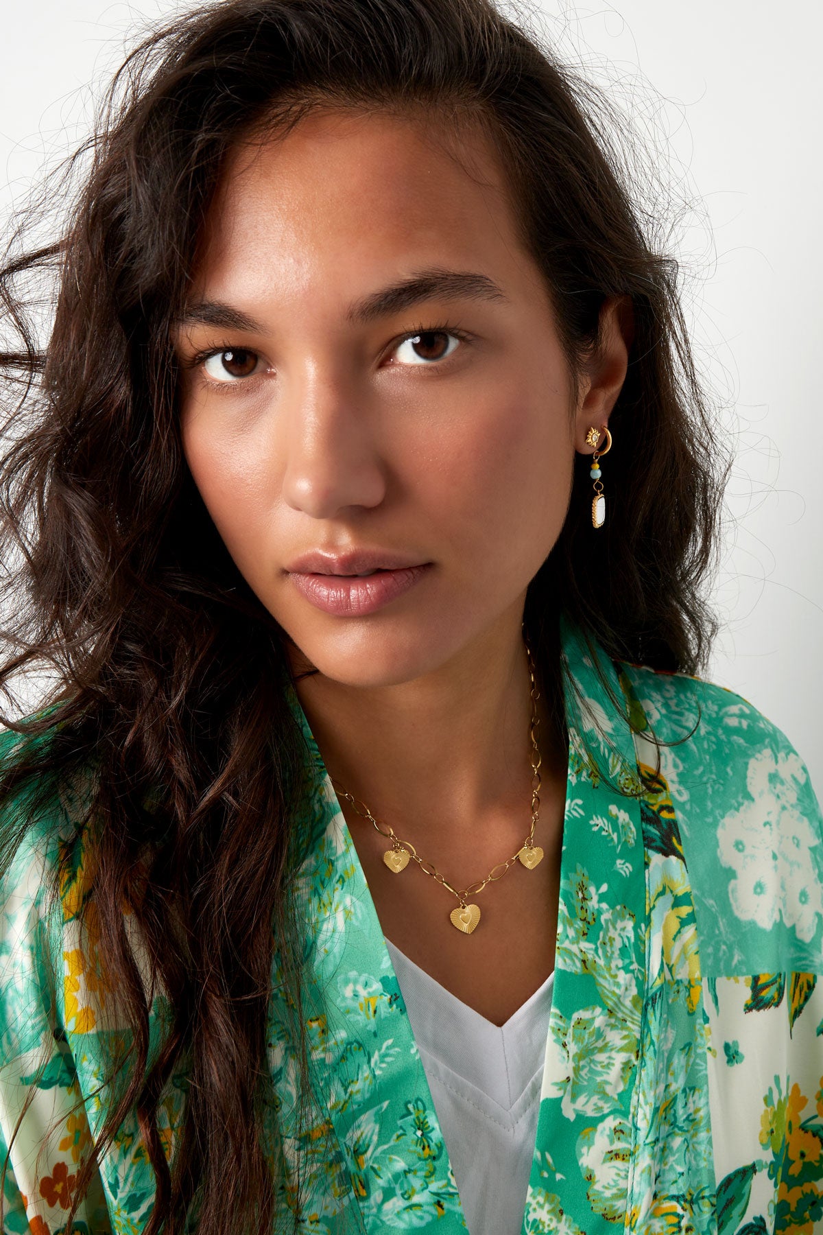 Model showcasing the gold triple heart necklace paired with a green floral top