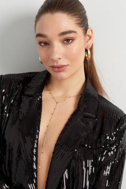 Model wearing gold delicate heart dangle necklace with a black sequin blazer
