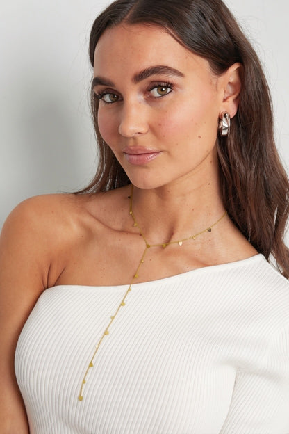 Cupids Drip: Delicate gold Y-necklace featuring small heart-shaped charms along a fine chain on a model.