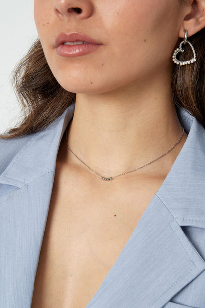 Side profile of woman showcasing silver ball chain necklace paired with heart-shaped pearl earrings